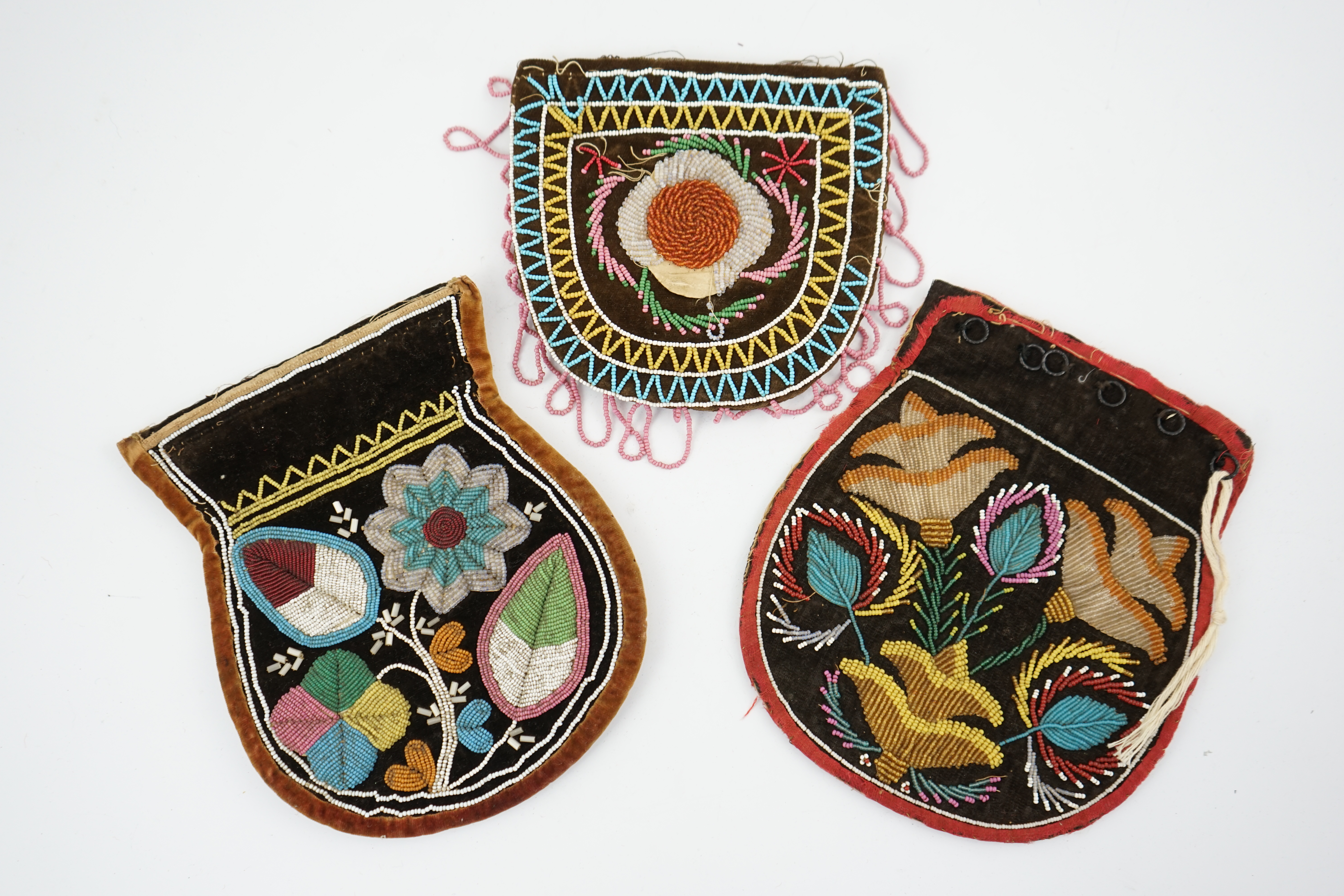 Three 19th century Native American bead worked pouches. A Wabanaki pouch/bag, worked in heart shaped fine coloured beads one side, the other side with flowers and leaves, embroidered on brown velvet, together with two Ir